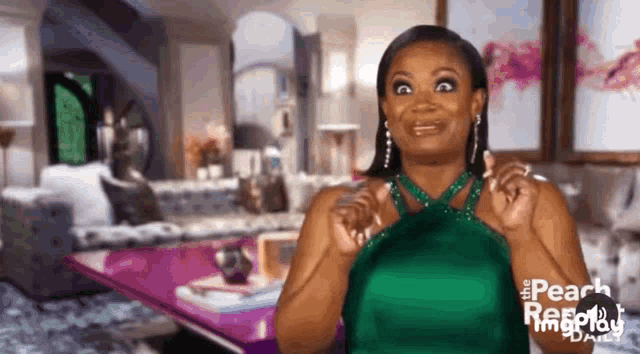 a woman in a green dress is making a funny face while standing in a living room .