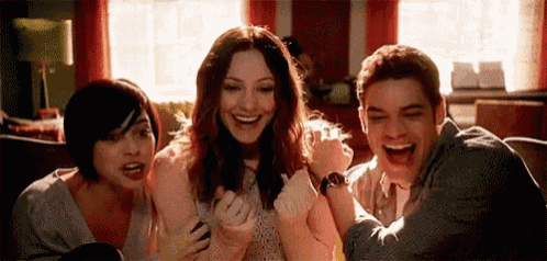 three people are sitting on a couch and laughing together .