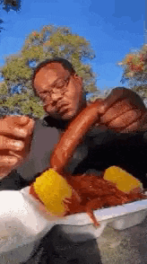 a man is eating a crawfish and corn on the cob .