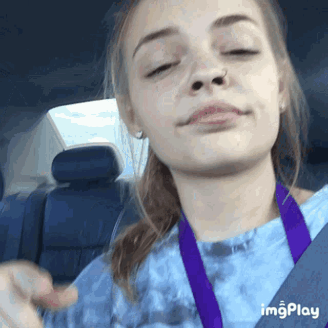 a girl in a car with a purple lanyard around her neck that says imgplay on the bottom