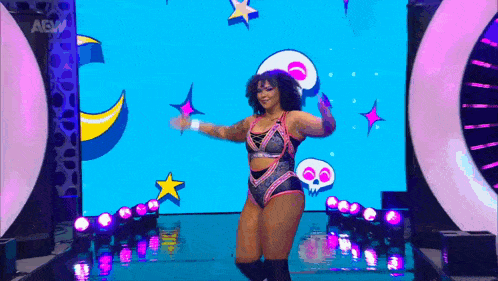 a woman is dancing on a stage in front of a large screen with a skull on it .