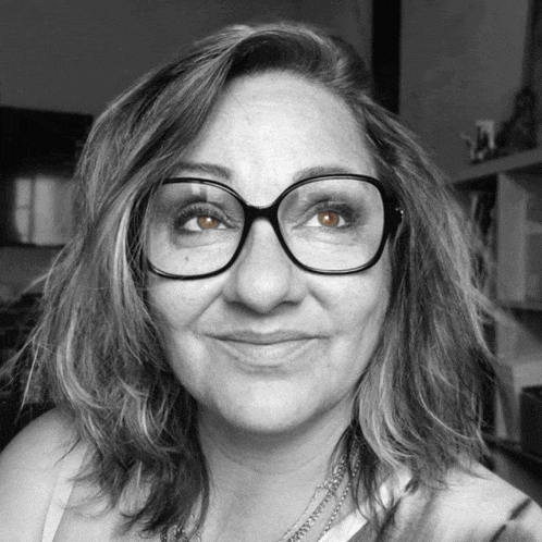 a woman wearing glasses is smiling for the camera