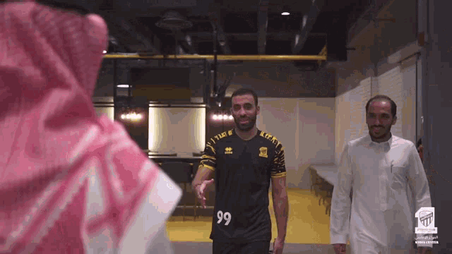 a man wearing a jersey with the number 99 on it shakes hands with another man