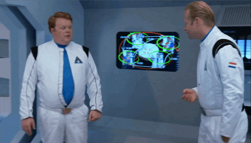 two men in space suits are talking in front of a screen that says ' a ' on it