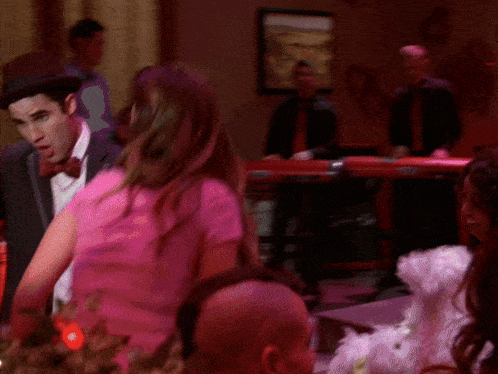 a woman in a pink shirt is dancing with a man in a suit and tie