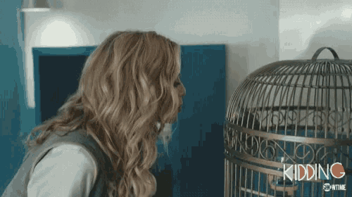 a woman standing next to a bird cage with the word kidding written on the bottom