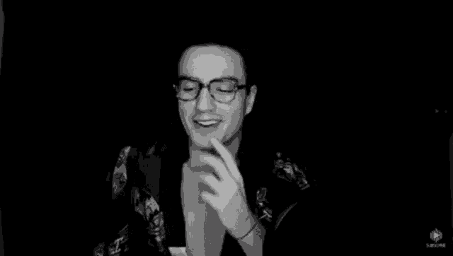 a black and white photo of a man wearing glasses and a robe laughing .