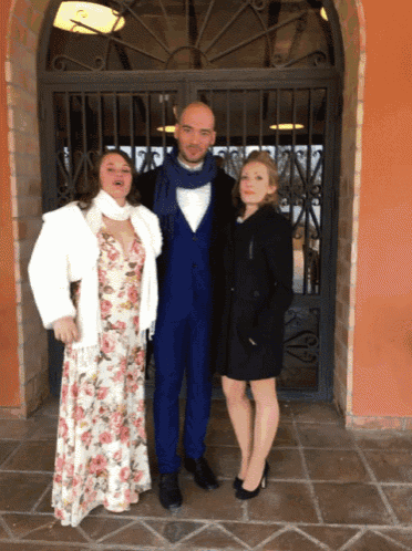 a man and two women pose for a picture in front of a fence