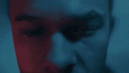 a close up of a man 's face with a blue and red background