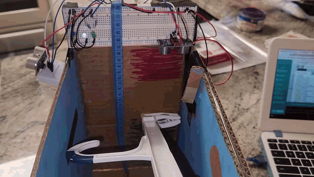 a cardboard box with a measuring tape on top of it and a laptop on the table