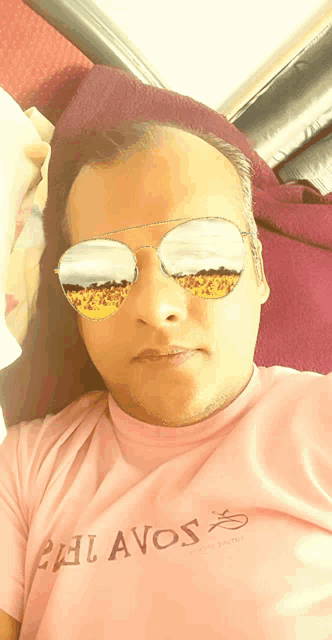 a man wearing sunglasses and a pink shirt that says palavos on it