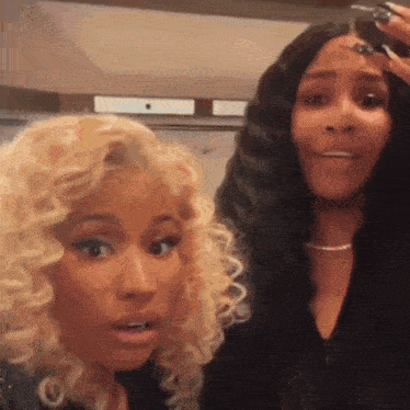 a couple of women are standing next to each other and one of them is wearing a wig .