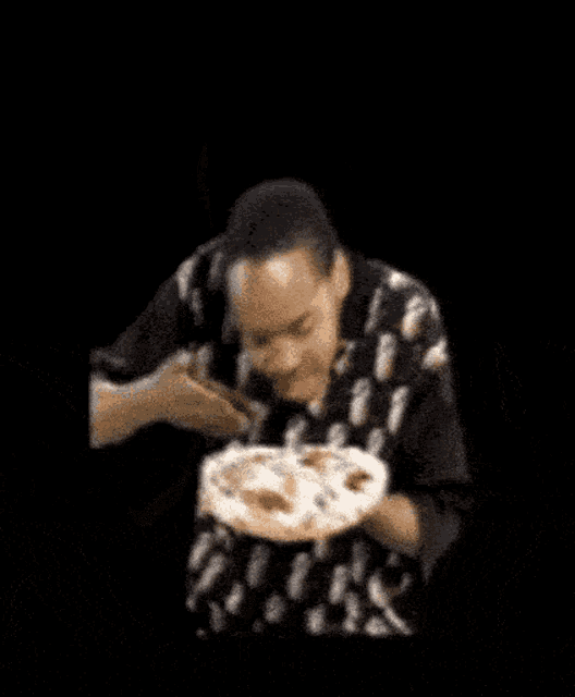 a man with dreadlocks is holding a plate of food in front of his face