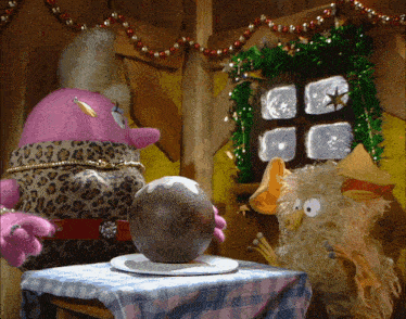 two stuffed animals are sitting at a table with a large egg on it