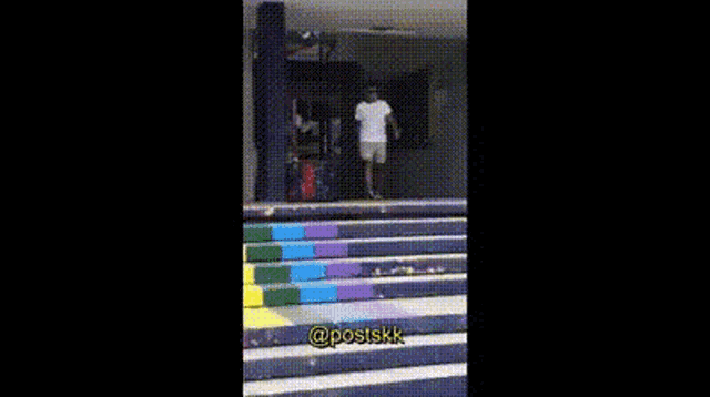 a man in a white shirt and shorts is walking down stairs with a woman behind him .