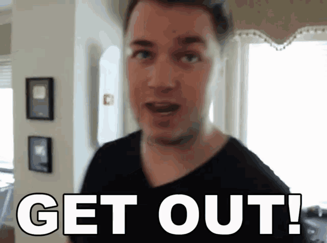 a man in a black shirt says " get out " in white letters