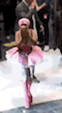a woman in a pink dress and pink boots is walking down a runway .
