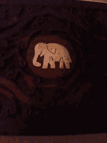 a wood carving of an elephant with the letters aa and a on it