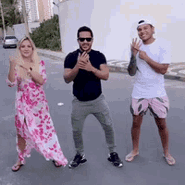 a woman in a pink dress is standing next to two men