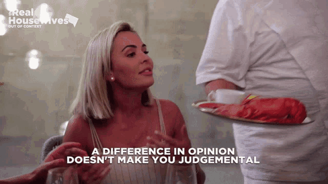 a woman in a white dress is talking to a man holding a tray of food with the words a difference in opinion