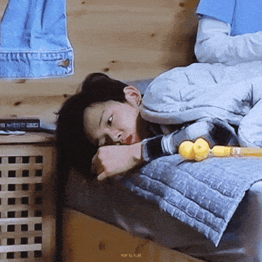 a young boy is laying on a bed with a blanket and a toy in his hand