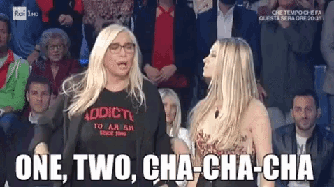 two women are standing in front of a crowd and one of them is wearing a black shirt that says addicti