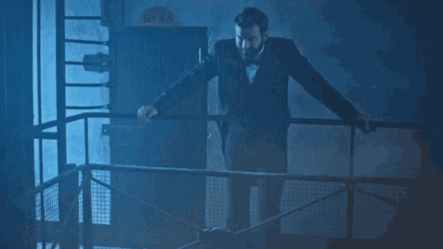 a man in a suit is standing on a railing in front of a sign that says n ° 85