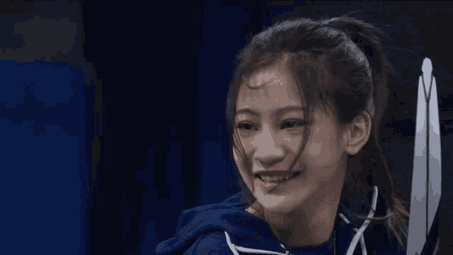 a girl with a ponytail is smiling and wearing a blue shirt