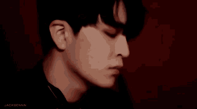 a close up of a young man 's face in front of a red background .