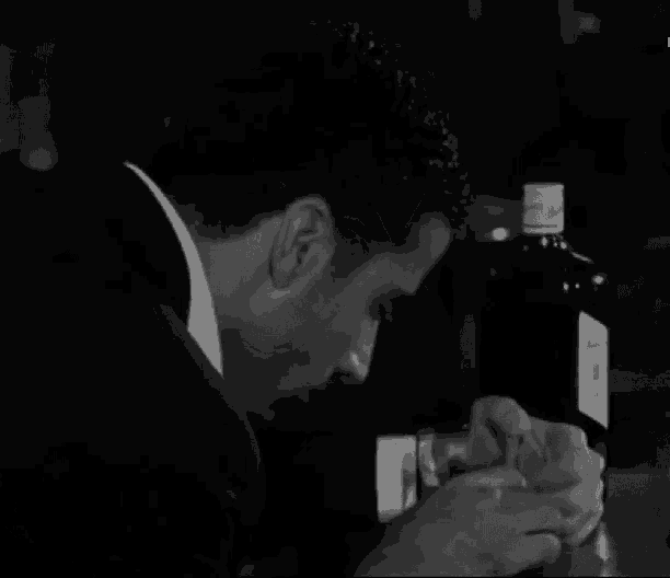 a man in a suit is holding a bottle of alcohol