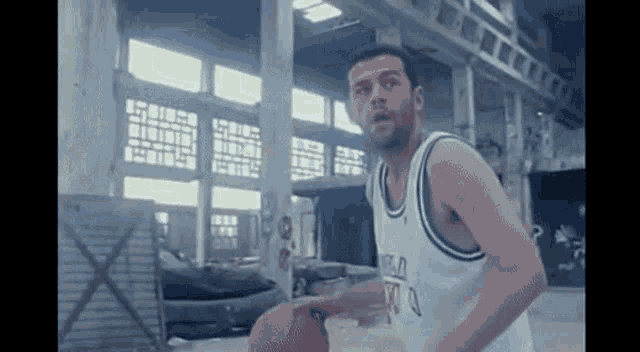 a man in a basketball uniform is holding a basketball in a building .