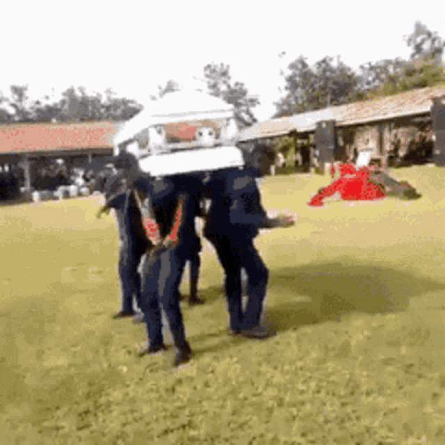 a group of people are carrying a coffin on their heads