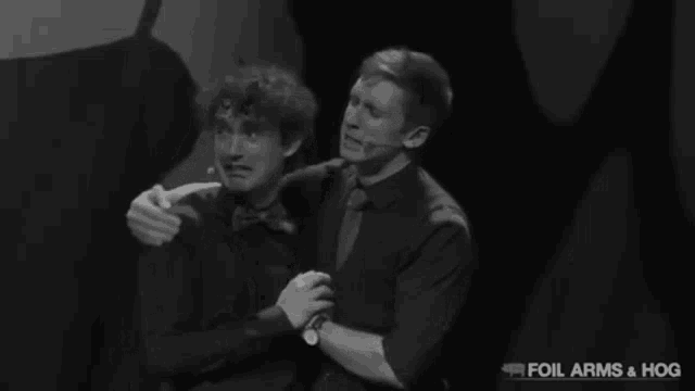 a black and white photo of two men hugging with the words " foil arms & hog " on the bottom right
