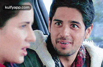 a man and a woman are looking at each other in a car .