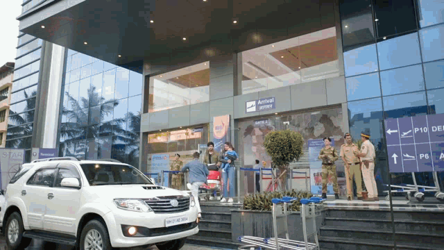 a white suv is parked in front of a building that says arrival office