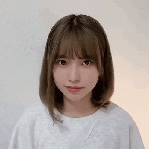 a young woman with short hair and bangs is wearing a white t-shirt .