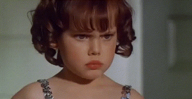 a little girl with a serious look on her face is wearing a bra
