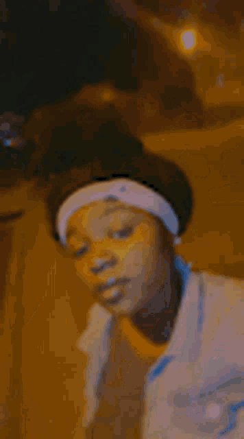 a woman wearing a headband and a white shirt is standing in the dark .