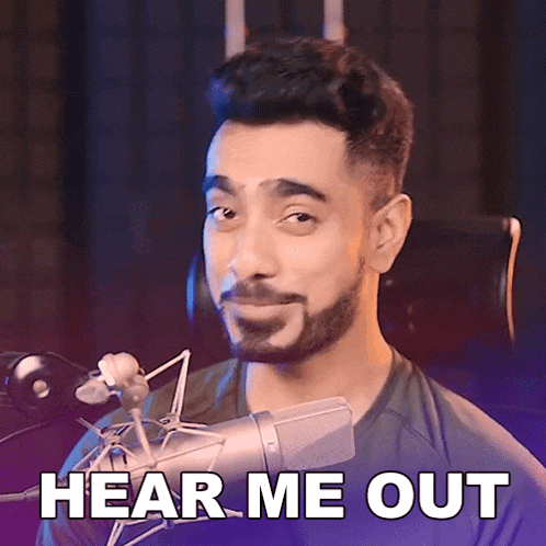 a man with a beard is holding a microphone and says " hear me out "