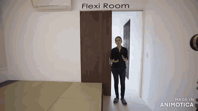 a woman is standing in a room with a sliding door that says flexi room on it .