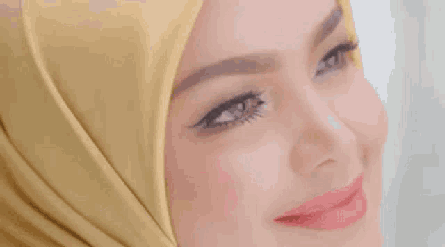 a close up of a woman 's face wearing a yellow hijab .