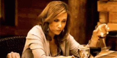 a woman is sitting at a table with a glass of wine and a plate of food .