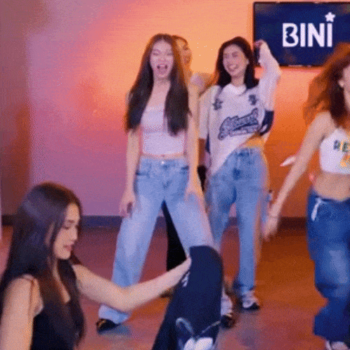 a group of young women are dancing in front of a tv that says bini