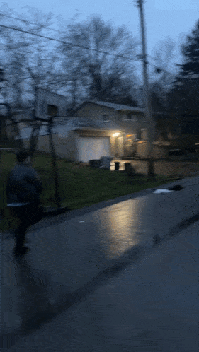 a blurry picture of a person walking down a street with a house in the background