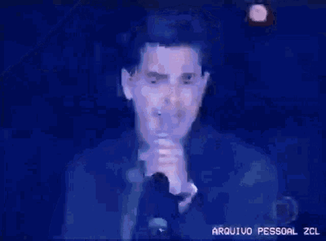 a man is singing into a microphone with the words arquivo pessoal zcl below him