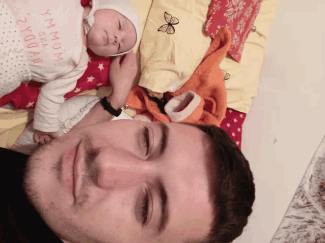 a man is holding a baby who is wearing a shirt that says daddy and mum
