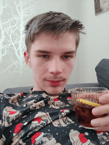a man wearing a christmas shirt is holding a cup of tea