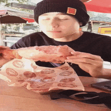 a man wearing a beanie with a cartoon character on it eating a large piece of meat