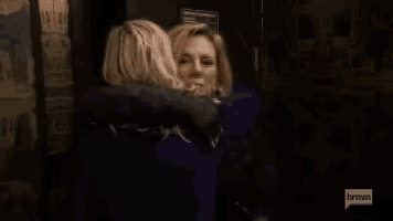two women hugging in front of a door that says bravo