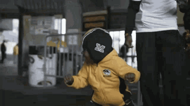 a child wearing a yellow jacket with the letter m on the front